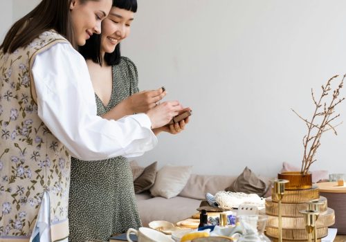 Two women enjoying a creative DIY project indoors. Various craft supplies around them.